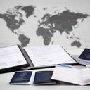 Trademark folder, passport stamps, and a lawyer’s desk with international filing documents arranged beside a world map print